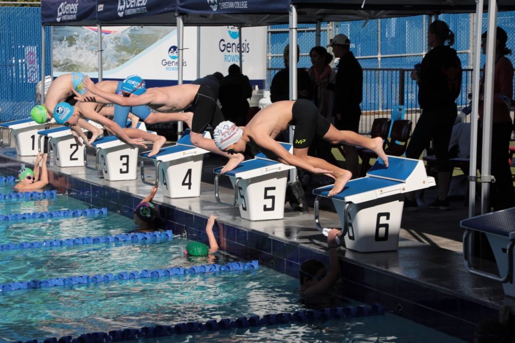 a group of people diving into a swimming pool.